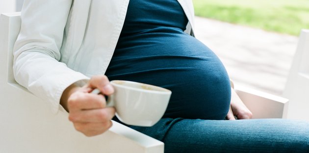 Pregnant woman sitting with cup of coffee
